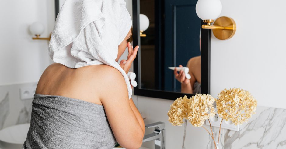 жена си слага крем пред огледало